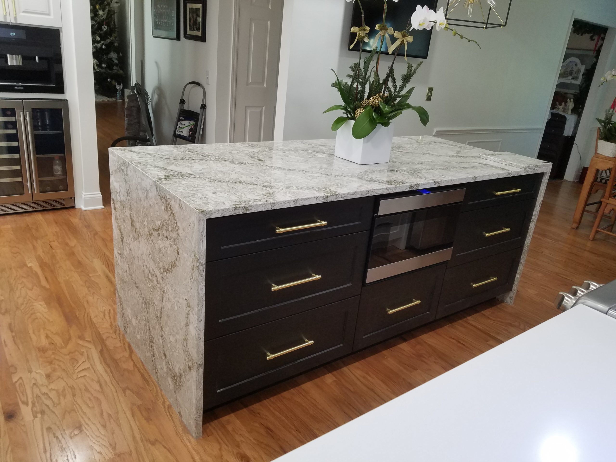 Waterfall white and gray marble island with dark brown cabinets