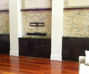 Dark stained wood cabinets on an all brick wall